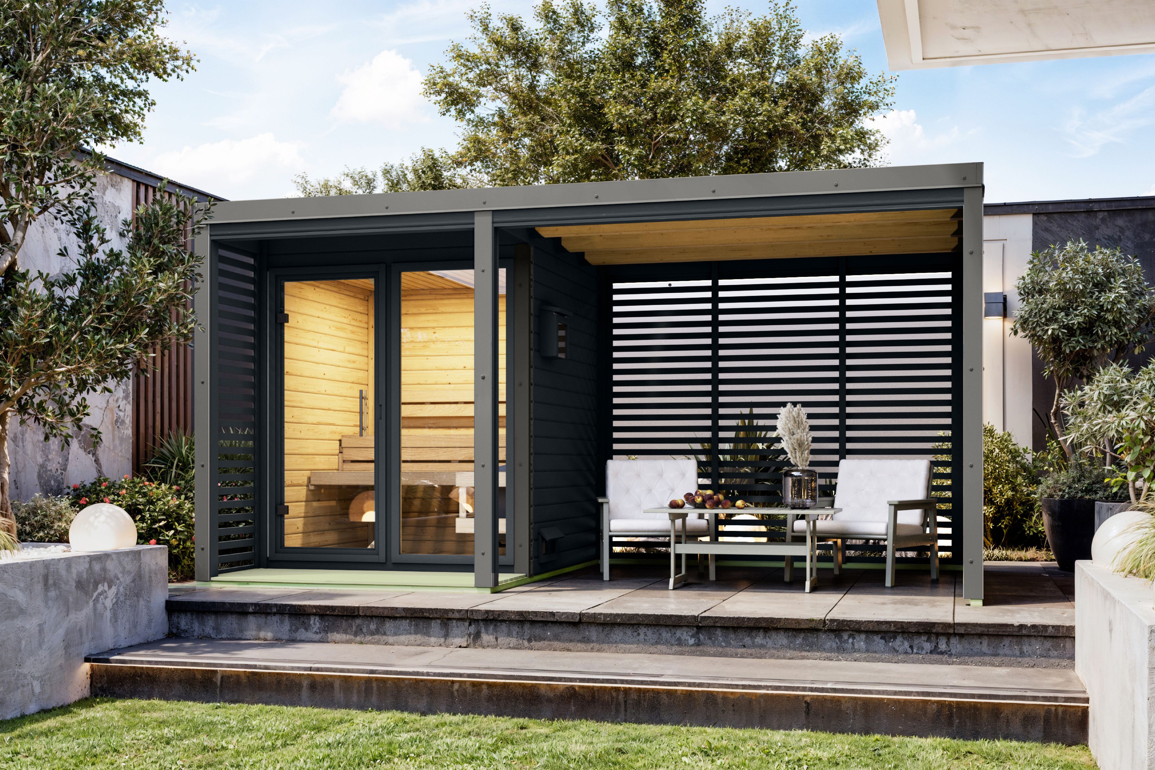 Karibu Saunahaus Ares 1 mit 2,70 m Anbaudach als Gartensauna aus Massivholz im Garten mit Glasfront